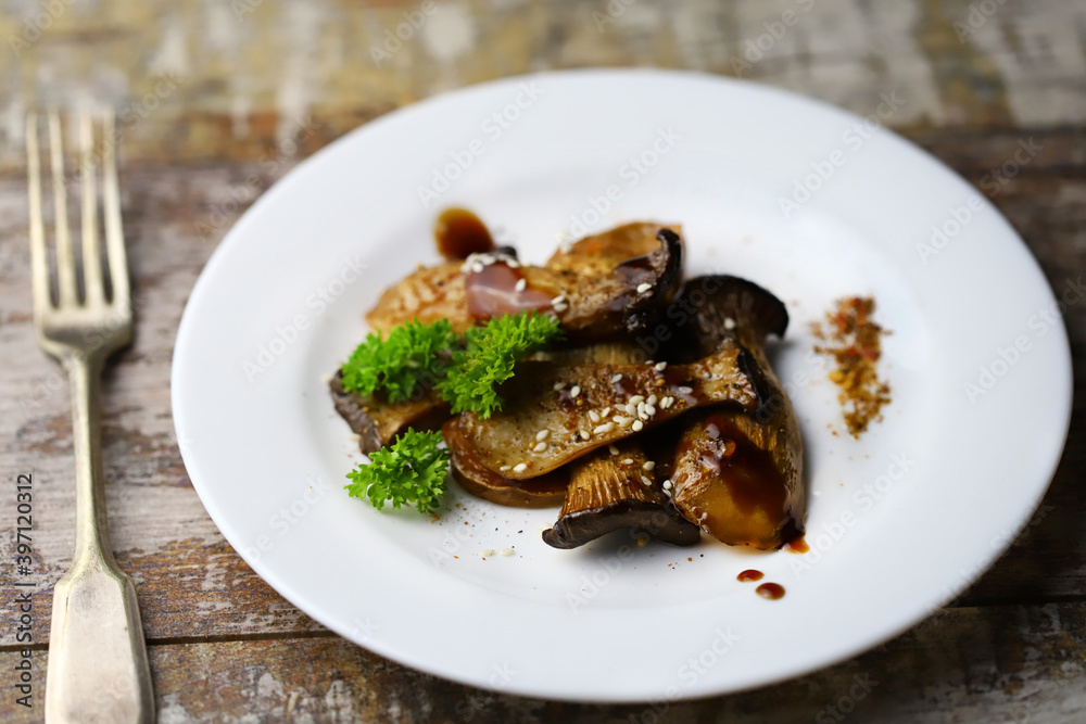 Close-up. Selective focus. Fried eringi mushrooms, served on a white plate. Close-up. Selective focus. Fried eringi mushrooms, served on a white plate.