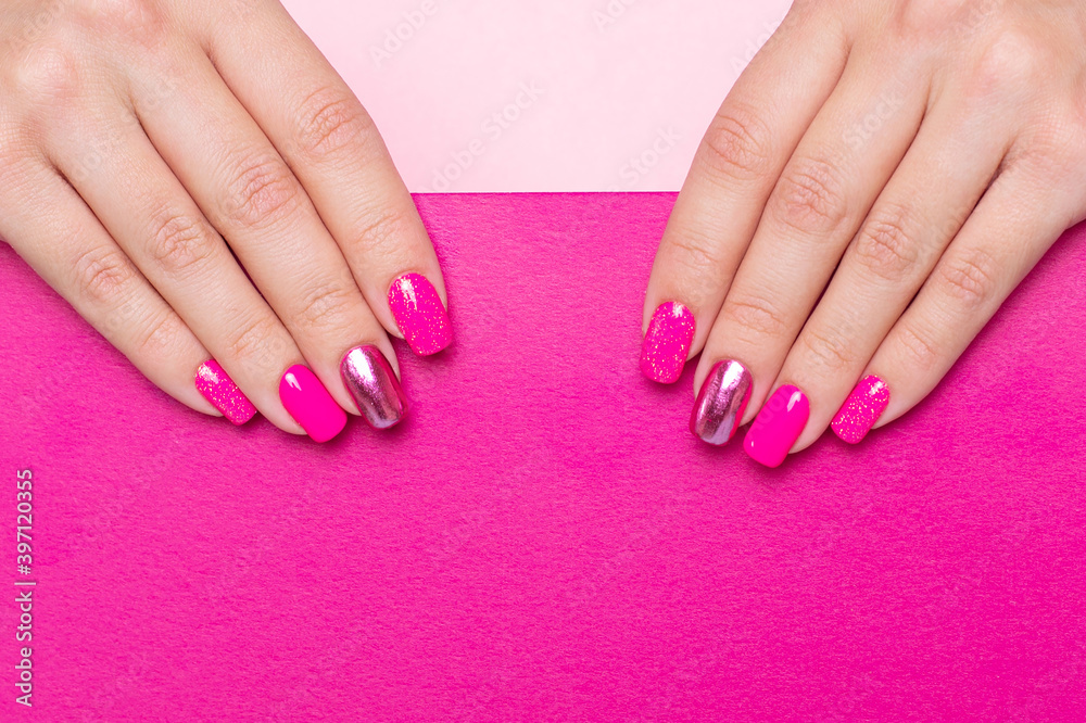 Beautiful female hand with festive manicure nails, with copy space on pink background