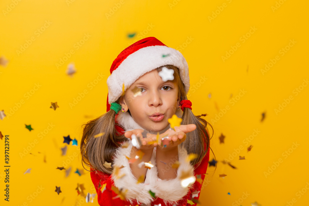 Little girl wearing Santa costume blowing away colorful confetti