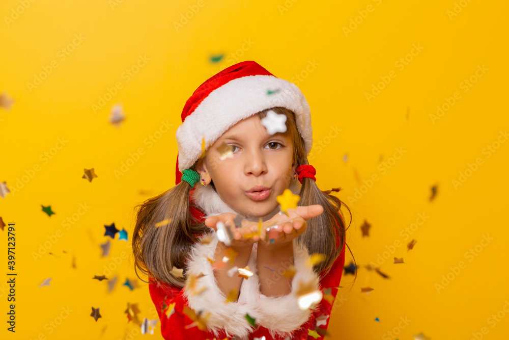 Little girl wearing Santa costume blowing away colorful confetti Little girl wearing Santa costume blowing away colorful confetti