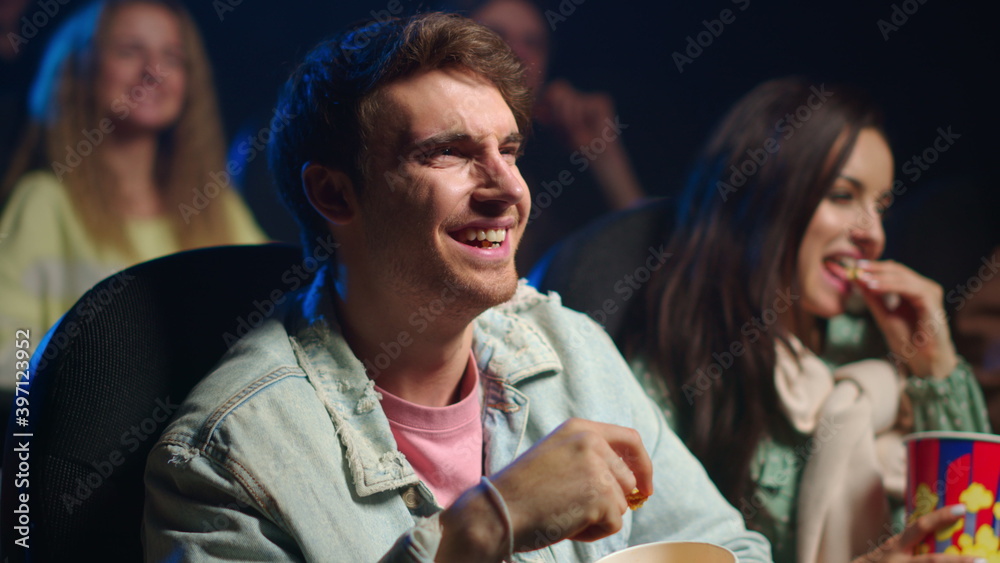 Cheerful woman having fun in cinema. Happy couple eating in movie theater.