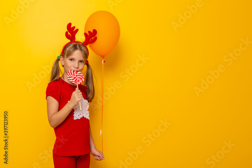 Little girl holding a balloon and eating lollipop