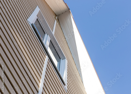 The facade of the new house clad with siding, with windows, against the blue sky.