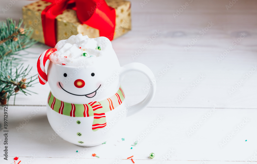 Hot chocolate in smiling snowman mug in Christmas setting Hot chocolate in smiling snowman mug in Christmas setting