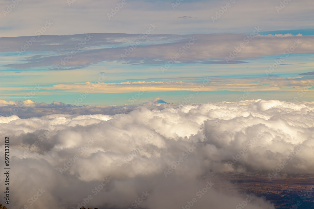 Obraz premium High angle shot of forest on hills covered with clouds and background volcano pico de orizaba