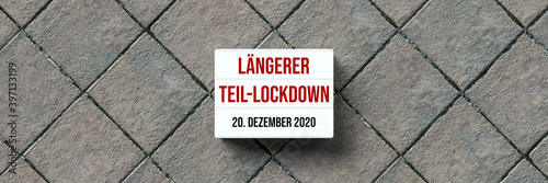 lightbox with the German message for PROLONGUED PARTIAL LOCKDOWN - 20TH OF DECEMBER 2020 on stone pavement background