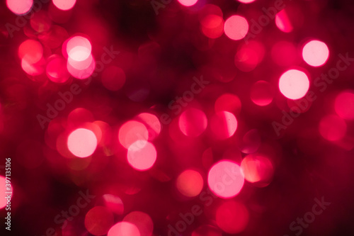 Selective focus. Garlands of glowing lights in red, pink, and lilac colors. Blurry Christmas tree background.