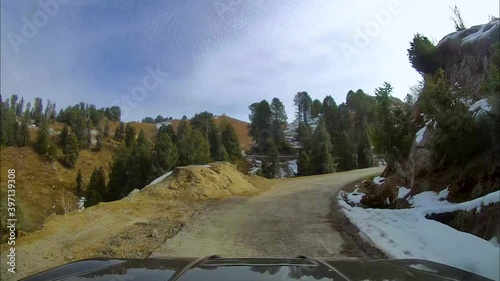 SUV driving through narrow and steep mountainous roads covered with snow during winters. View through dash camera.