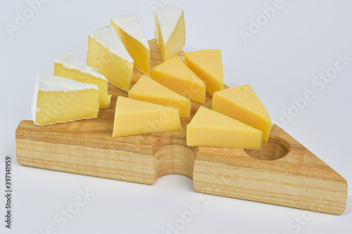 On a special wooden stand for cheese lie several pieces of different types of cheese on a white background