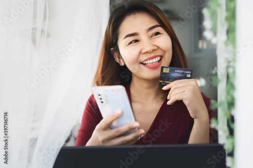 smile Asian girl happy shopping online from home hand holding credit card and smart phone © doucefleur