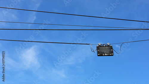 A black plastic box is hung on the wires. Fiber Optic Splitter Box (Plc / Coupler) for fiber optic splitter, high speed internet on blue background, with copy space. Selective focus