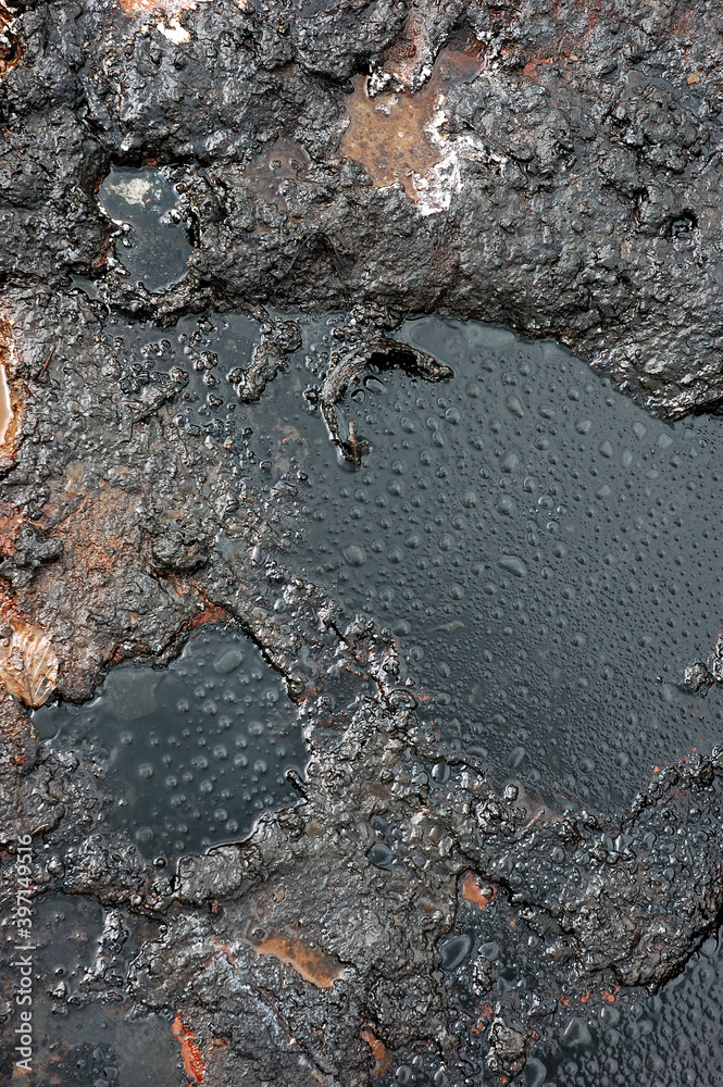 Fototapeta premium Watter drops on the petroleum surface.Spills of crude oil on the soil surface. Crater of the mud volcano.