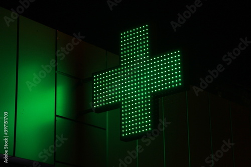 Glowing pixel cross of LED lamps on black background.