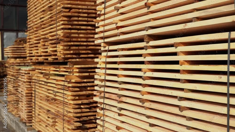 Warehouse for sawing boards on a sawmill outdoors. Timber mill, sawmill. Storage of planed wooden boards. Piles of wooden boards in the sawmill. Planking. Industry. Warehouse for sawing boards on a sawmill outdoors. Timber mill, sawmill. Storage of planed wooden boards. Piles of wooden boards in the sawmill. Planking. Industry.