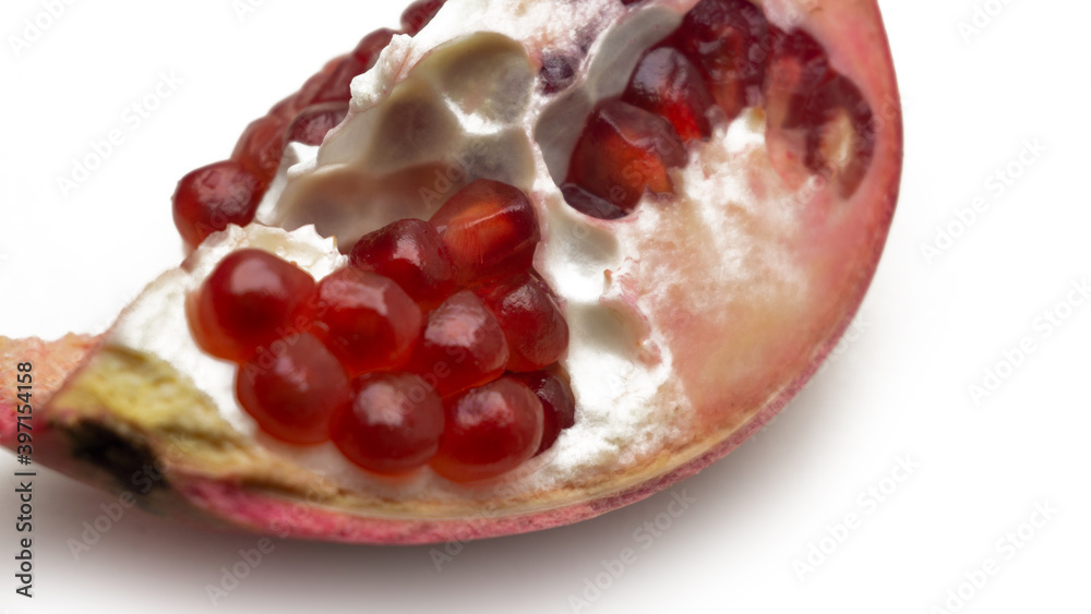 Close up texture of ripe red pomegranate fruit on isolated white background. Detail of pomegranate seeds inside the fruit. Close up texture of ripe red pomegranate fruit on isolated white background. Detail of pomegranate seeds inside the fruit.