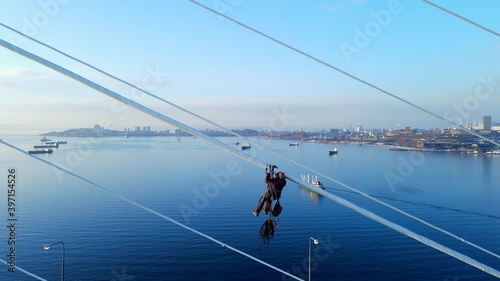 View from above. Close-up. The climber hangs on the cables and clears them of ice. Ice-covered as a result of an ice storm Russky Bridge to Vladivostok.