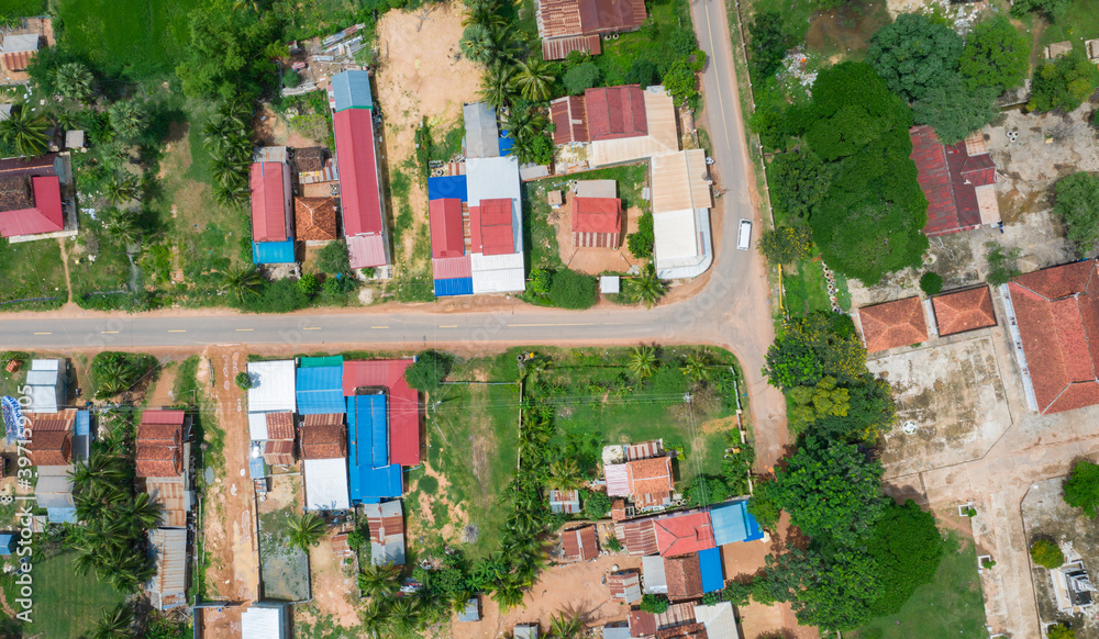 Obraz premium Main dirt road in rural village in Cambodia. There are houses on either side of the road.