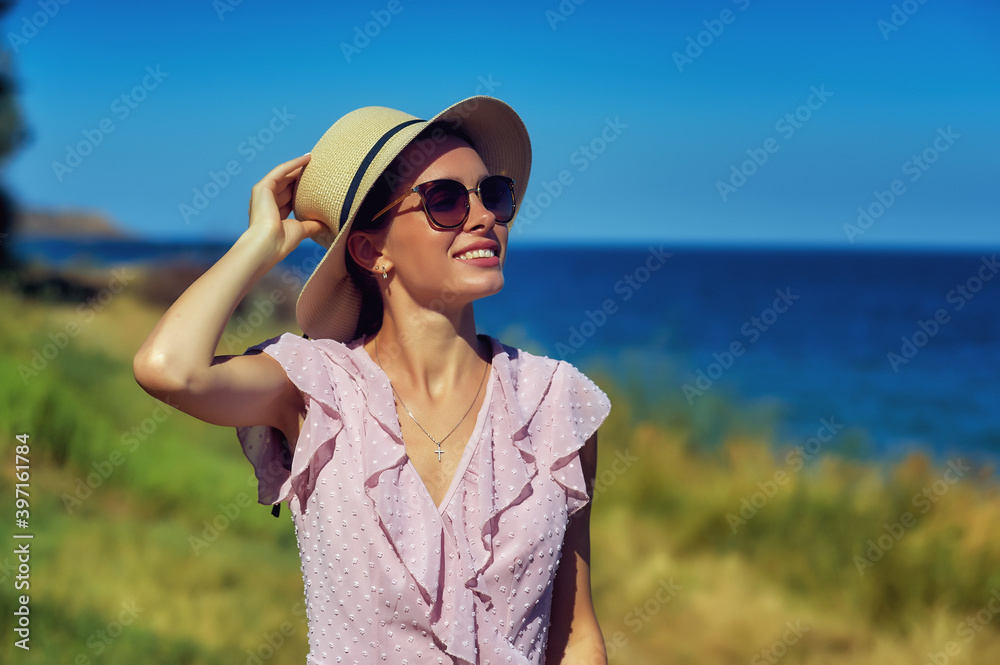 Beautiful girl in a summer dress and a fashionable hat in nature