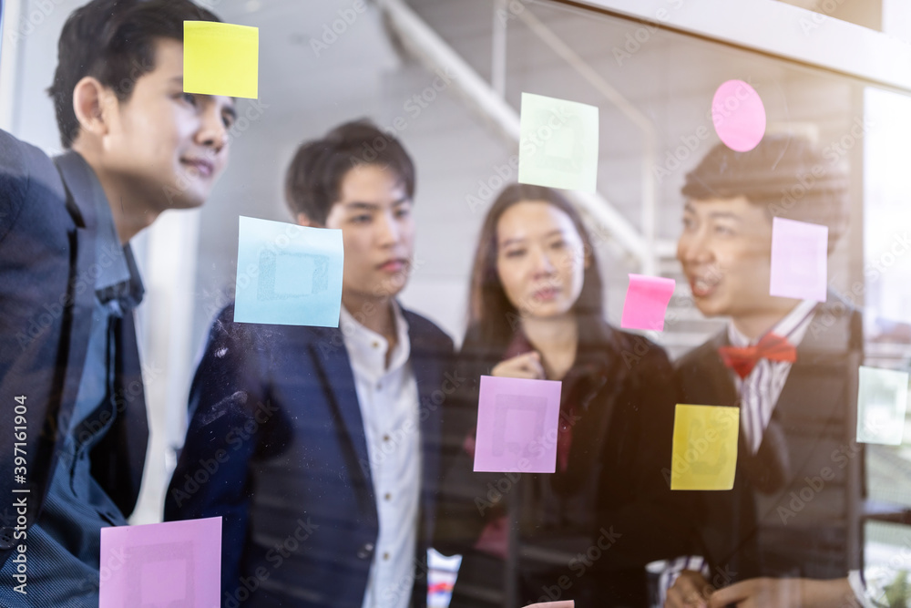 Group of asian business people with diverse genders (LGBT) Abstract blur with focus use post it notes to share idea.Brainstorming concept.Sticky note on glass wall in the meeting room at office Group of asian business people with diverse genders (LGBT) Abstract blur with focus use post it notes to share idea.Brainstorming concept.Sticky note on glass wall in the meeting room at office