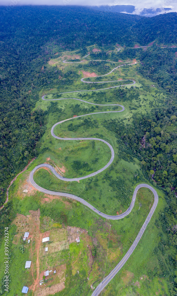 Winding road from the high mountain pass in Cambodia - Thailand  Great road trip trough the dense woods. Aerial view.