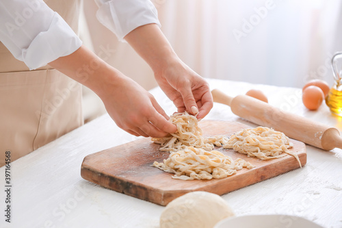 Woman making raw pasta in kitchen, closeup