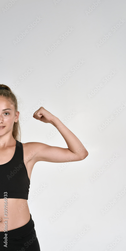 Cropped shot of cute sportive girl child in sportswear looking at camera, showing biceps while posing isolated over white background Cropped shot of cute sportive girl child in sportswear looking at camera, showing biceps while posing isolated over white background
