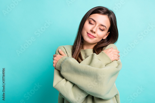 Photo portrait of calm woman hugging self isolated on vivid teal colored background © deagreez