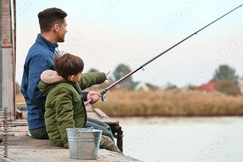 Little boy and his father fishing on river