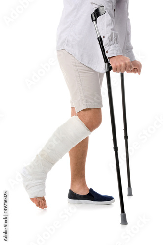 Young man with broken leg on white background
