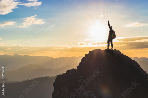 Silhouette Success male hiker with arms outstretched on top of mountain