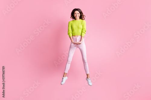 Full length photo of pretty girl jump hold hands wear green pullover pants sneakers isolated pink color background © deagreez