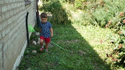 Llittle boy running on the grass with a butterfly net in his hands. Cute little boy playing outside photo