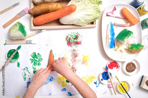 Top view close up of toddler boy child hands, kid making artwork from vegetable stamping at home, Fun art and crafts for toddlers, Children's Art Project