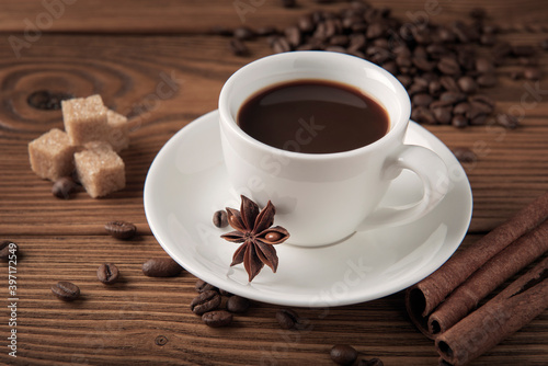 Cup of coffee with cane sugar and anise star on wooden textured table