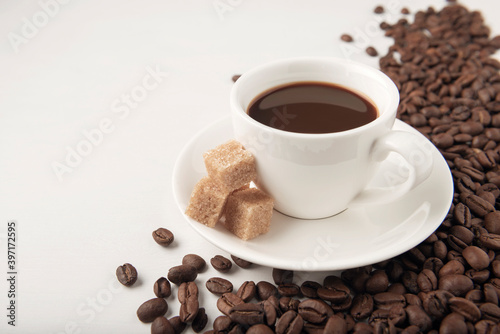 Cup of coffee with cane sugar and coffee beans on white background