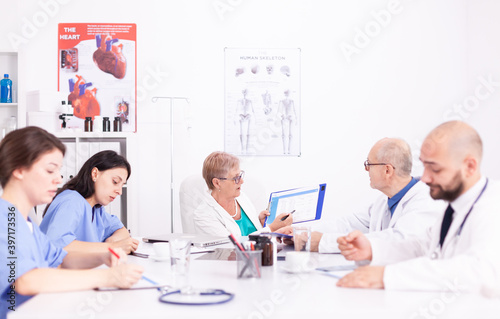 Female nurses taking notes while medical expert explaining about viral diseases in hospital conference room. Clinic expert therapist talking with colleagues about disease, medicine professional