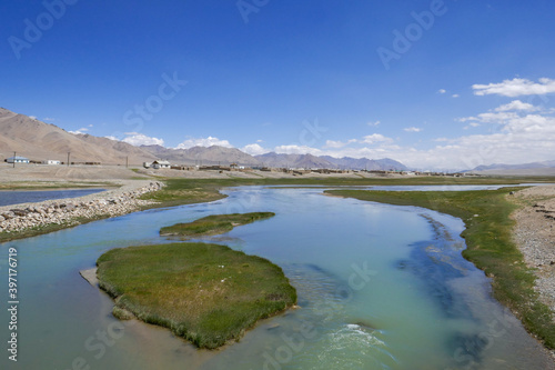 High-altitude kyrgyz Alichur village on the Pamir Highway, Murghab district, in the Gorno-Badakshan region of Tajikistan with turquoise Alichur river in the foreground and mountains in the background