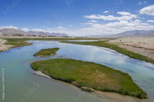 High-altitude kyrgyz Alichur village on the Pamir Highway, Murghab district, in the Gorno-Badakshan region of Tajikistan with turquoise Alichur river in the foreground and mountains in the background