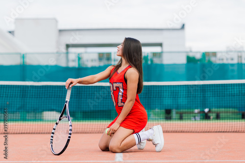 Beautiful female tennis player on tennis court. Red dress. © Ivan Zelenin