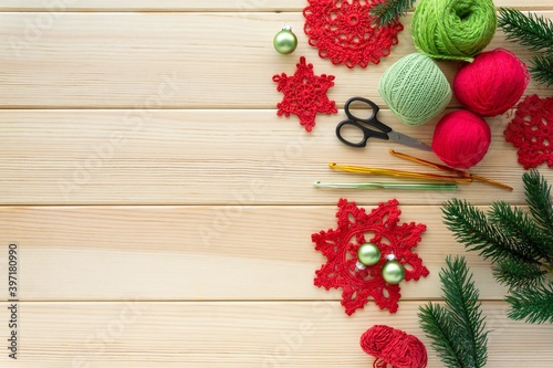 Christmas flat lay of items for needlework. Knitted snowflakes, threads and hooks on wooden background, copyspace