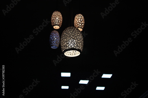 Round clay lampshades with different and asymmetrical lighting grooves, with yellow and white blue lighting, arranged on a balanced skyline and combining vertical lines on a dark & or light black.
