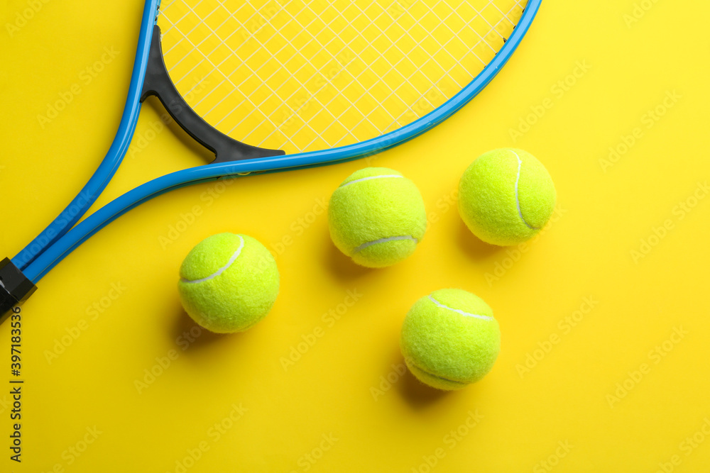 Tennis racket and balls on yellow background, flat lay. Sports equipment