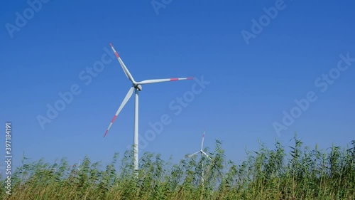 Wind turbine in farm on sunny day. Alternative and sustainable energy.