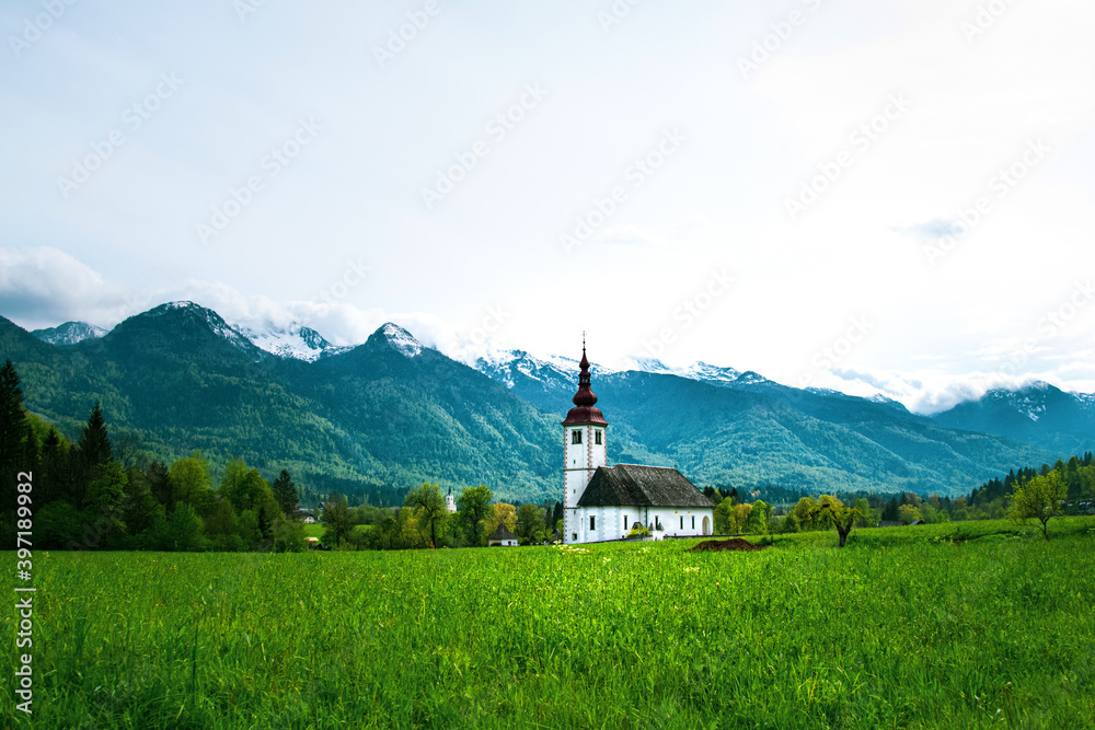 Beautiful view of the mountains and green meadows. In the background there is an old church. Slovenia Beautiful view of the mountains and green meadows. In the background there is an old church. Slovenia