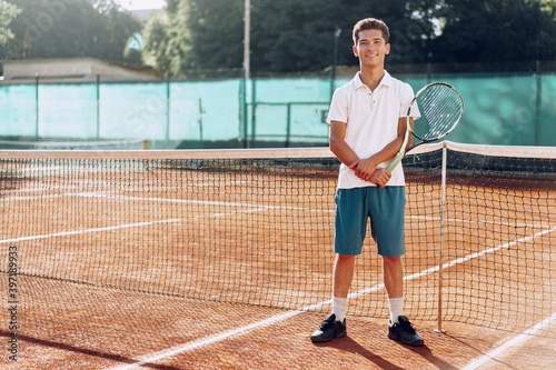 Young mixed race man tennis player with racket standing on tennis court