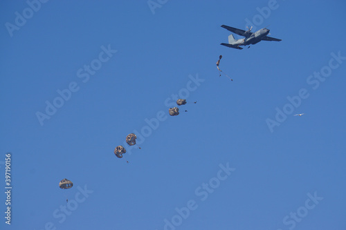 air force plane dropping army parachute jumpers on a clear blue day