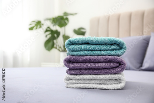 Stack of clean towels on bed indoors. Space for text