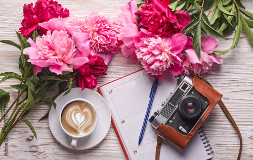 Obraz na płótnie Flat lay women's office desk. Female workspace with laptop, pink peonies bouquet, camera and coffee on white background. Top view feminine background. w salonie