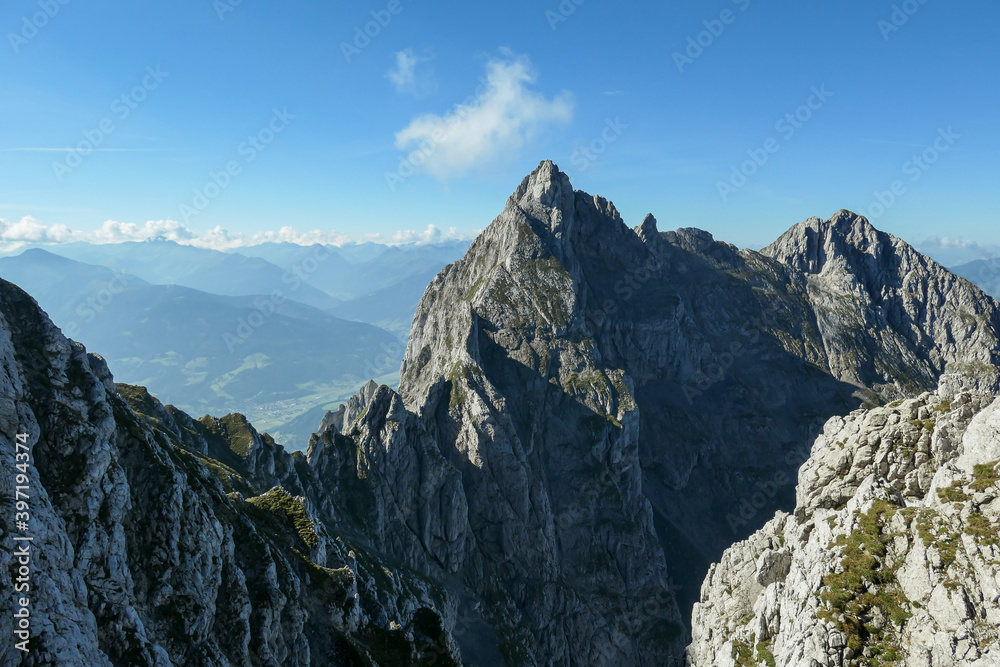 A panoramic view on Alpine slopes in Austria. There are sharp ans steep mountains and high peaks around. The Alpine slopes are almost barren, just moss overgrowing the slopes. Serenity and freedom.