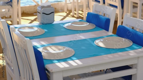 Traditional Aegean fish restaurant, tables and chairs next to see in Gumusluk Town, Bodrum, Turkey at sunny day. Bodrum is very popular and famous place for tourist.